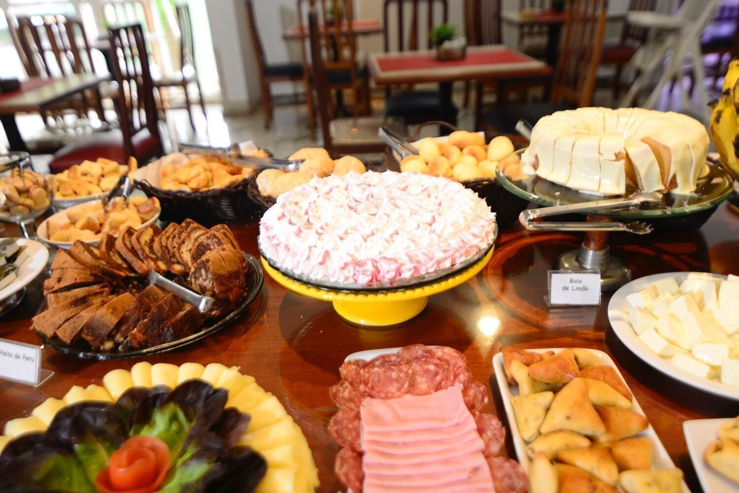 Buffet com diversos pratos, incluindo bolo, carne e queijo.