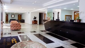 Un hall d’hôtel comprenant un comptoir d’accueil, un espace salon et un guichet d’enregistrement.