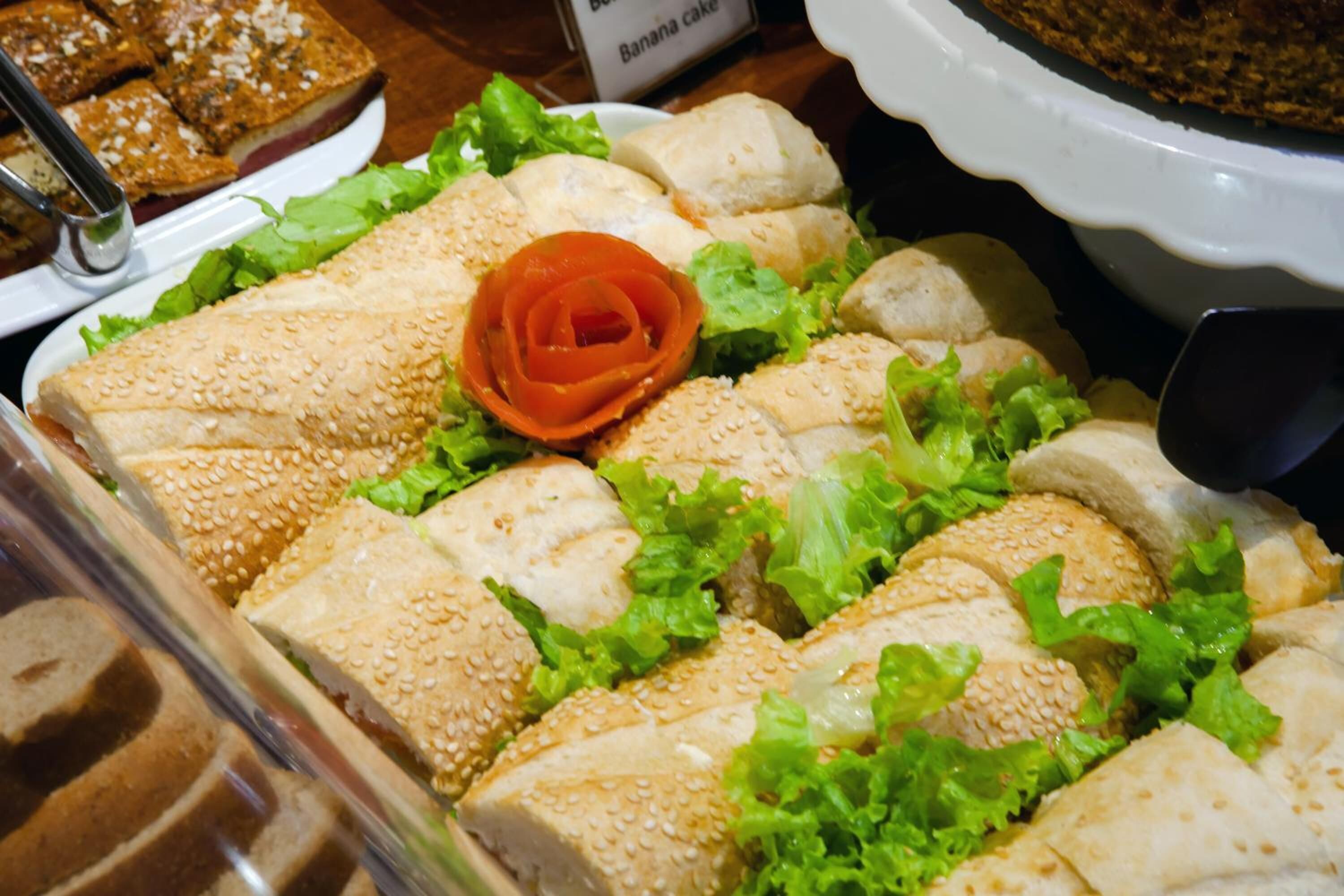 A sandwich platter with sesame seed bread, lettuce, and a decorative red rose.