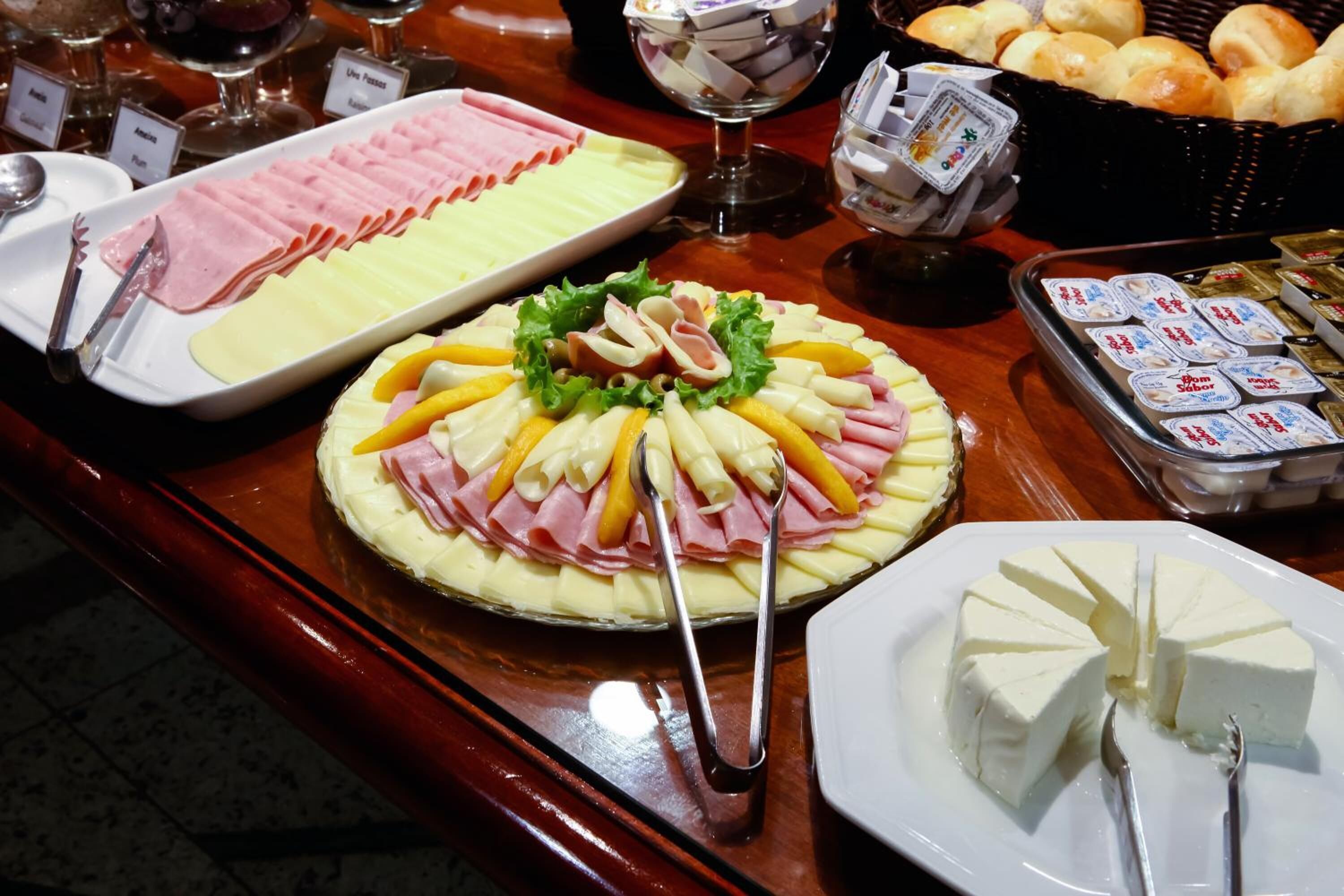 A buffet table with various food items including a large platter of cheese, ham, and vegetables, and a tray of butter cubes.