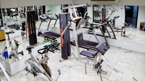 Une salle de sport équipée de divers appareils d’exercice, notamment des tapis de course, des vélos d’appartement et des appareils de musculation.