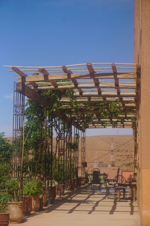A covered outdoor area with a pergola, potted plants, and outdoor furniture.