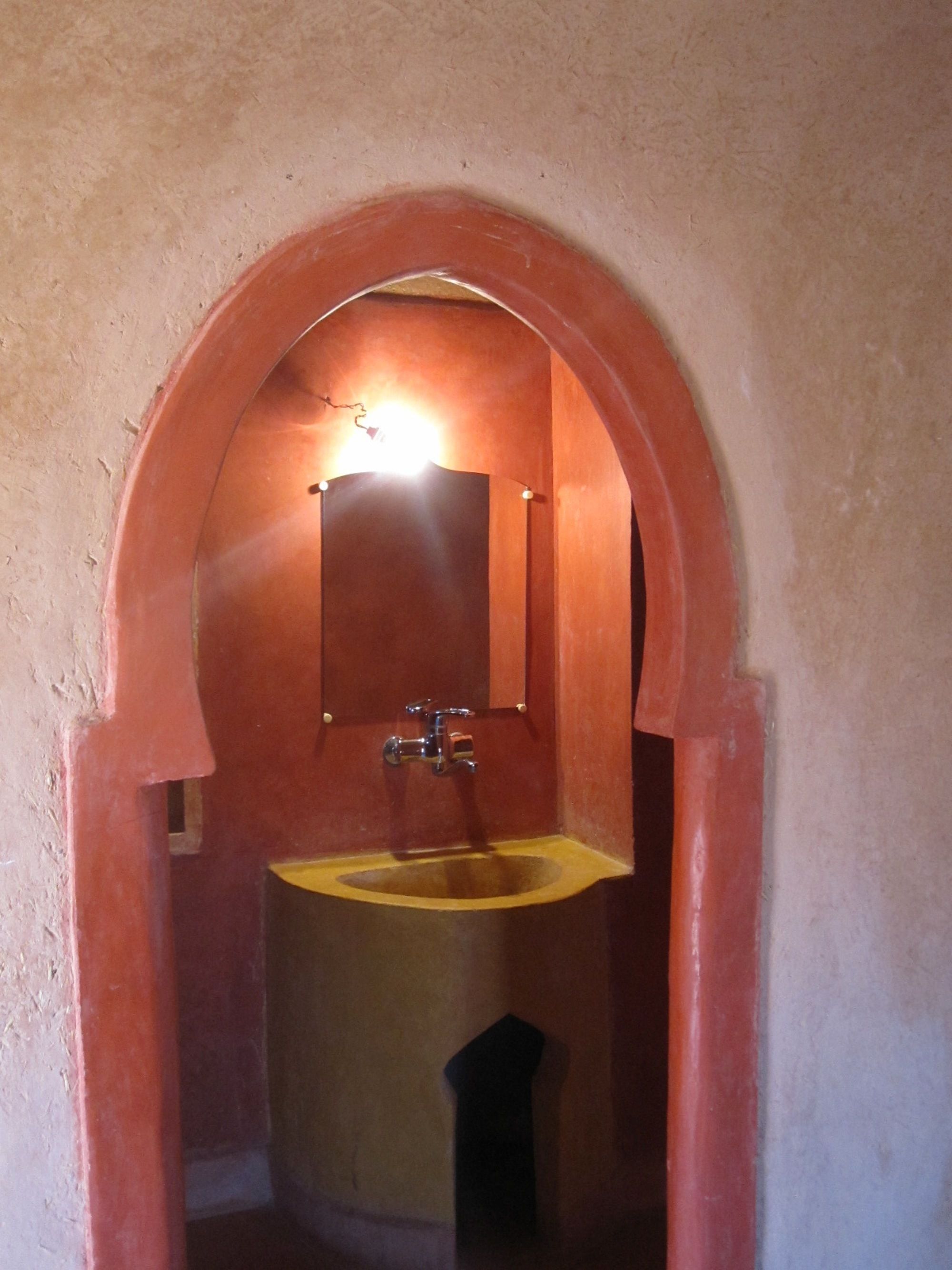 A bathroom with a round sink, a mirror, and a light fixture above the mirror.