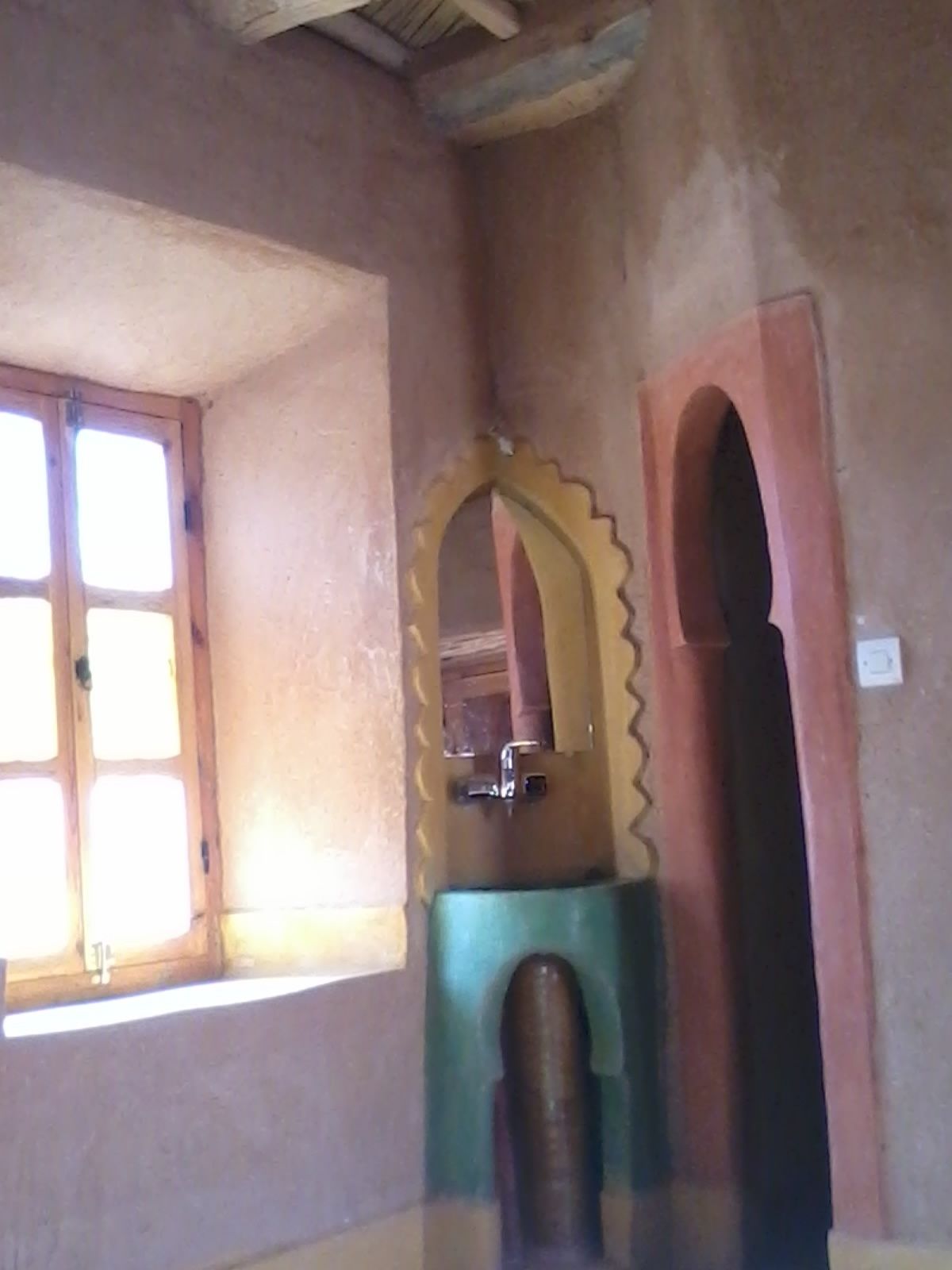 A room with a window, a sink, and a mirror.