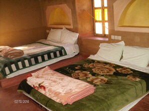 A hotel room with two beds, each with a distinct bedspread.