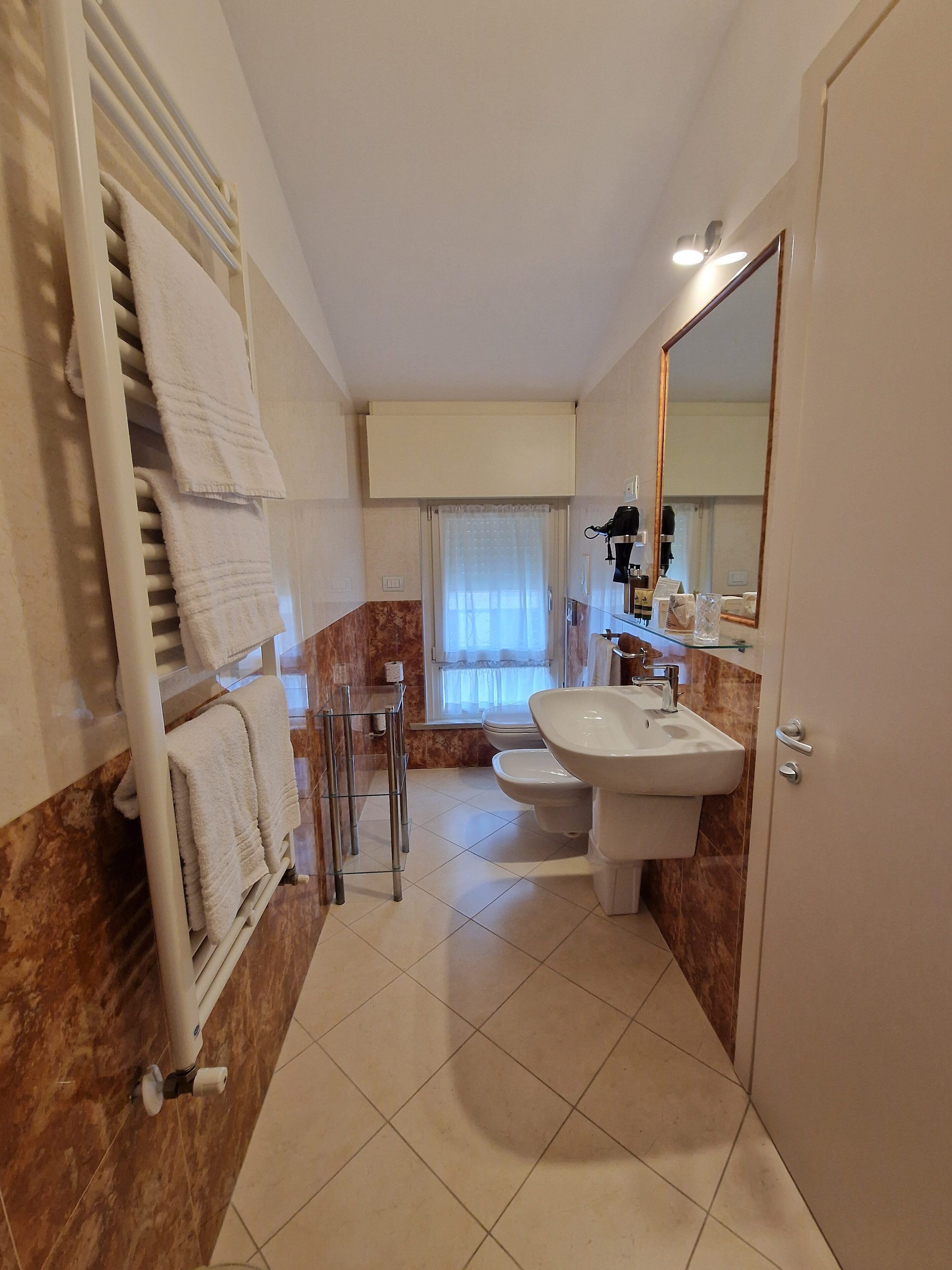 Un bagno con un lavandino bianco, uno specchio, un portasciugamani e un water.