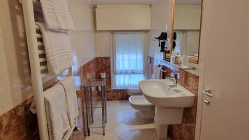 Un bagno con un lavandino bianco, uno specchio, un portasciugamani e un water.