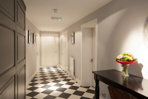 A hallway with a checkered floor, a vase of flowers on a table, and a door at the end. - City Retreat Edinburgh (Edinburgh)