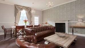 Un salon spacieux avec un canapé en cuir marron, une table basse en bois et une cheminée.
