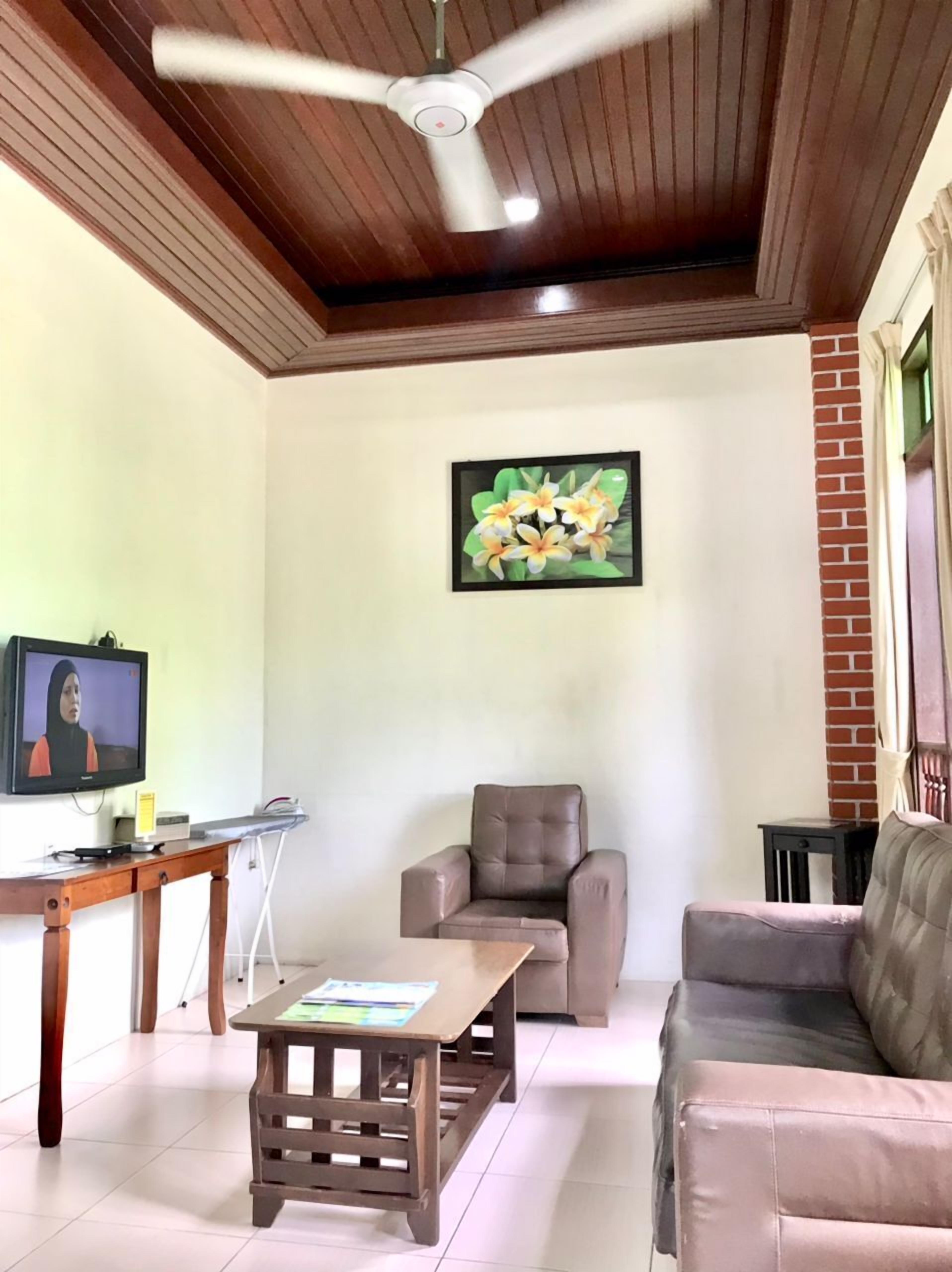 A living room with a ceiling fan, a television, a coffee table, a sofa, and a chair.