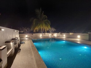 A rooftop swimming pool with a tiled floor, surrounded by walls and a palm tree. - Jasmine Villa Tropical Garden (Langkawi)