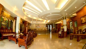 Un hall de hotel con mostrador de recepción, muebles de madera y un diseño de techo moderno.
