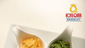A bowl of soup with lime wedges, a bowl of chips, a bowl of cilantro, and a bowl of chili flakes.