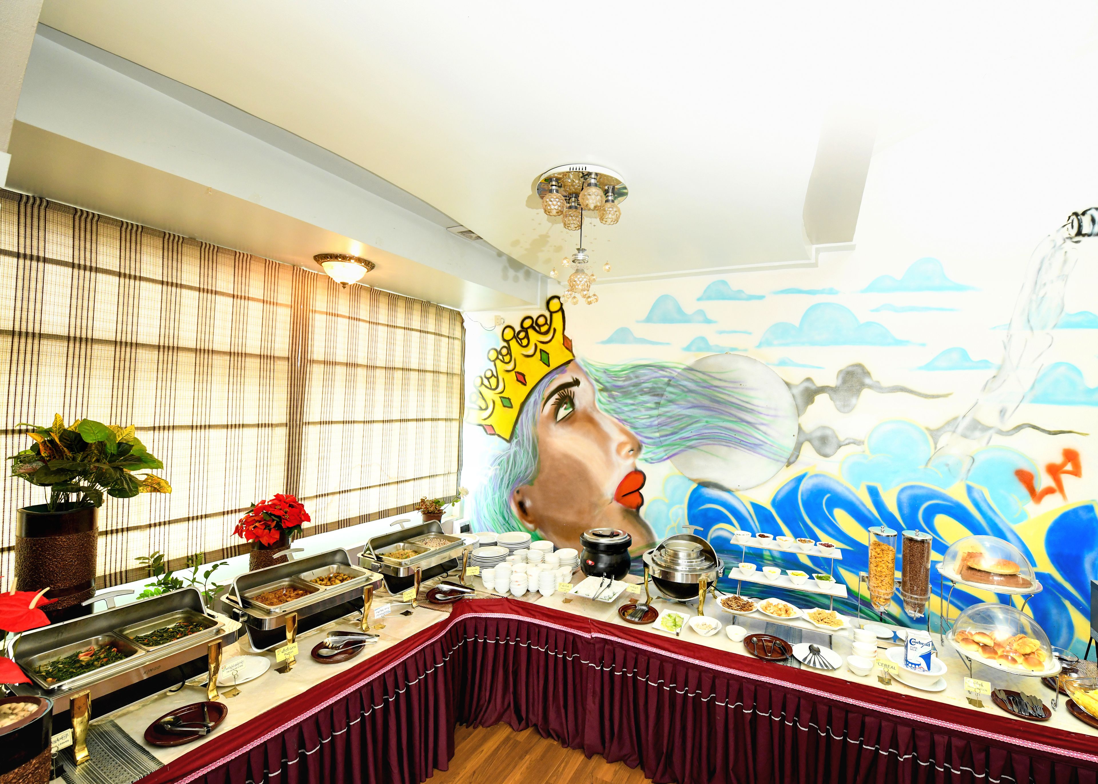 A buffet setup with various food items and a mural on the wall.