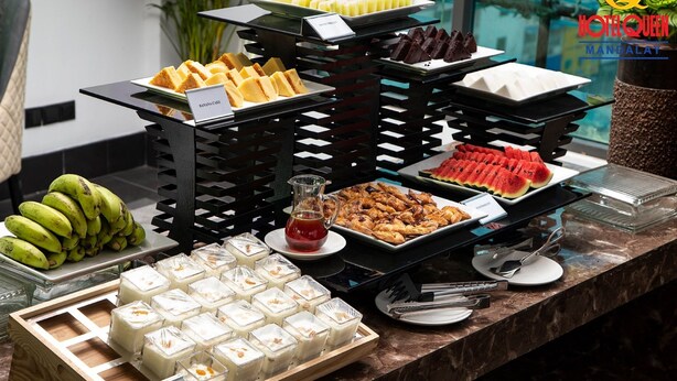 Un bufé con diversas opciones de comida, incluyendo plátanos, pasteles y postres.