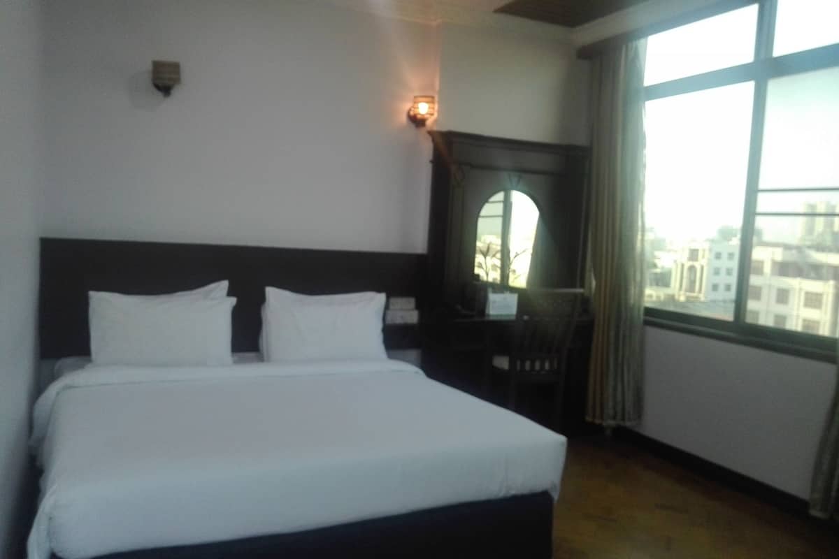 Een hotelkamer met een groot bed, een bureau en een raam met uitzicht op de stad.
