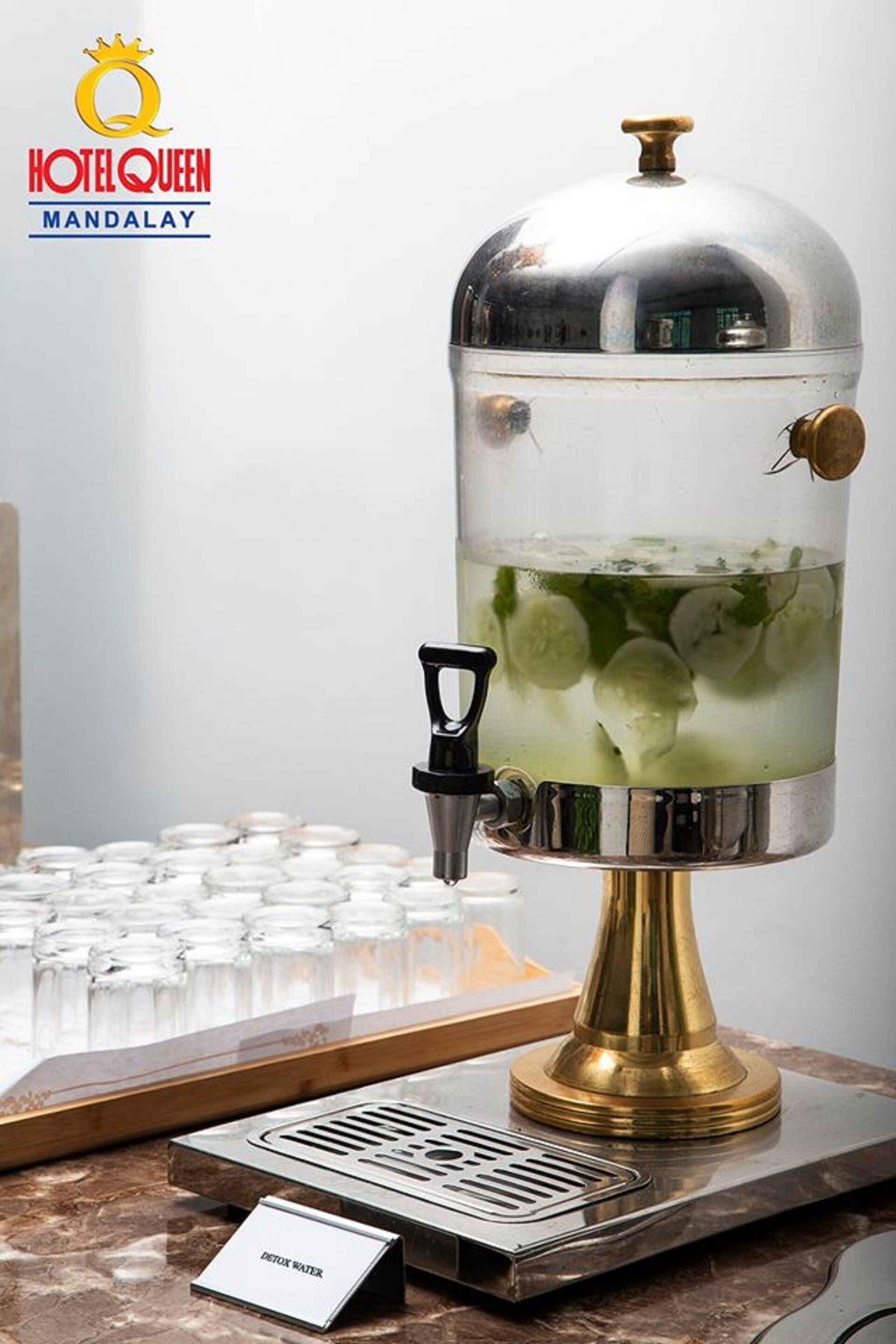 A water dispenser with a clear container, mint leaves, and a brass base.