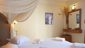 A hotel room with a bed, a bedside table, a mirror, and a wall-mounted picture. - Theo Beach Hotel (Rethymnon)