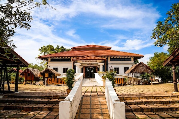 A traditional building with a red-tiled roof, a central entrance with steps, and a sign reading "Selamat Datang Welcome". - Chenang Inn (Langkawi)