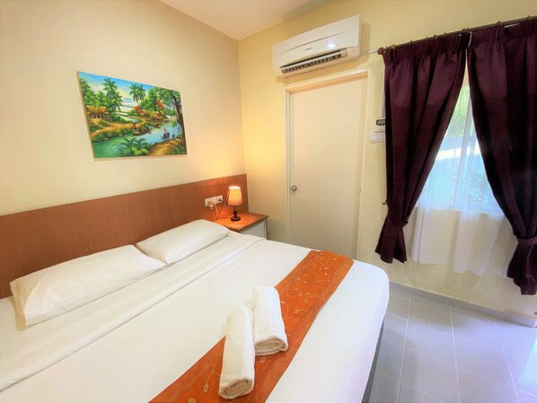 Una camera d'albergo con un letto, un condizionatore, un quadro, un comodino, una lampada e una finestra con tende.