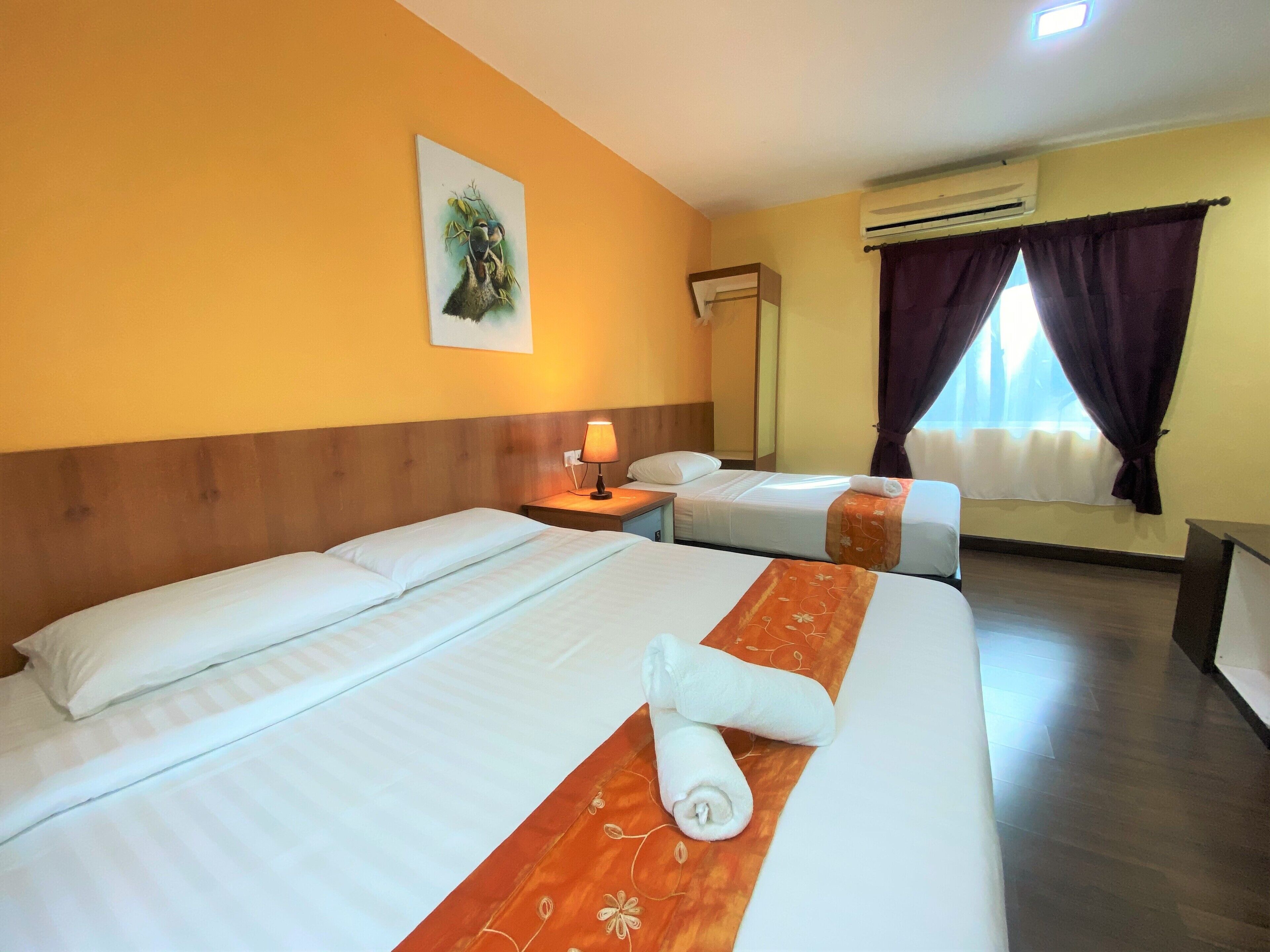 Habitación de hotel con dos camas, una mesita de noche con lámpara, un cuadro en la pared y un aire acondicionado.