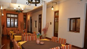 A dining area with striped chairs and tables, a vase with flowers, and a chandelier. - Hotel La Giralda (Salta)