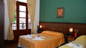 A hotel room with two beds, a green wall, a framed picture, and a window with curtains. - Hotel La Giralda (Salta)