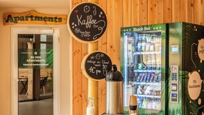 Un café avec une enseigne indiquant qu’il est ouvert jusqu’à 1h30 du matin, un distributeur automatique de collations et une porte portant l’inscription « Appartements ».