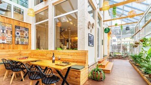 Un café chaleureux avec des meubles en bois, un jeu d’échecs et une plante verte.