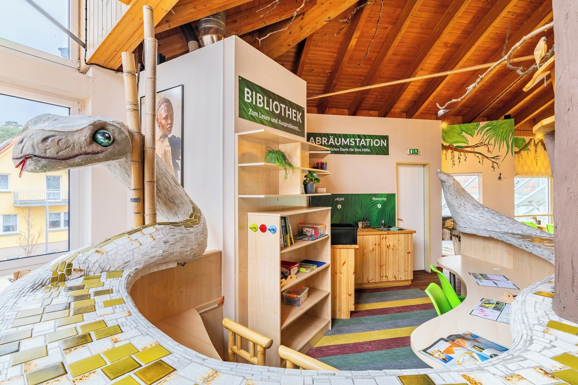 A library with wooden bookshelves, a reception desk, and a colorful striped carpet.