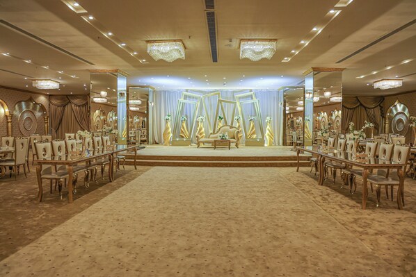 A grand ballroom with a stage, ornate chandeliers, and a carpeted floor. - Reef Global Hotel (Makkah)
