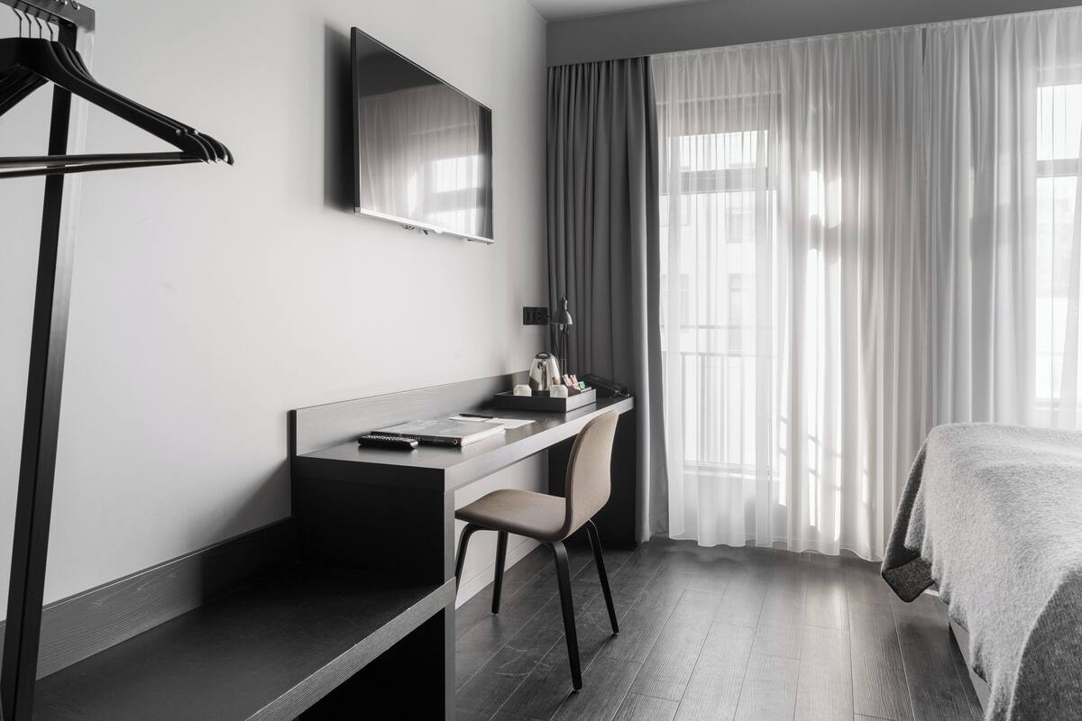 Ein modernes Hotelzimmer mit Schreibtisch, Stuhl und Bett.
