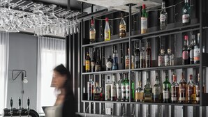 Zona de bar con estantes de botellas de licor, barra y una persona en movimiento.