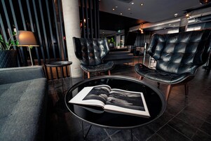 A modern lounge area with leather chairs, a round table with an open book, and ambient lighting.