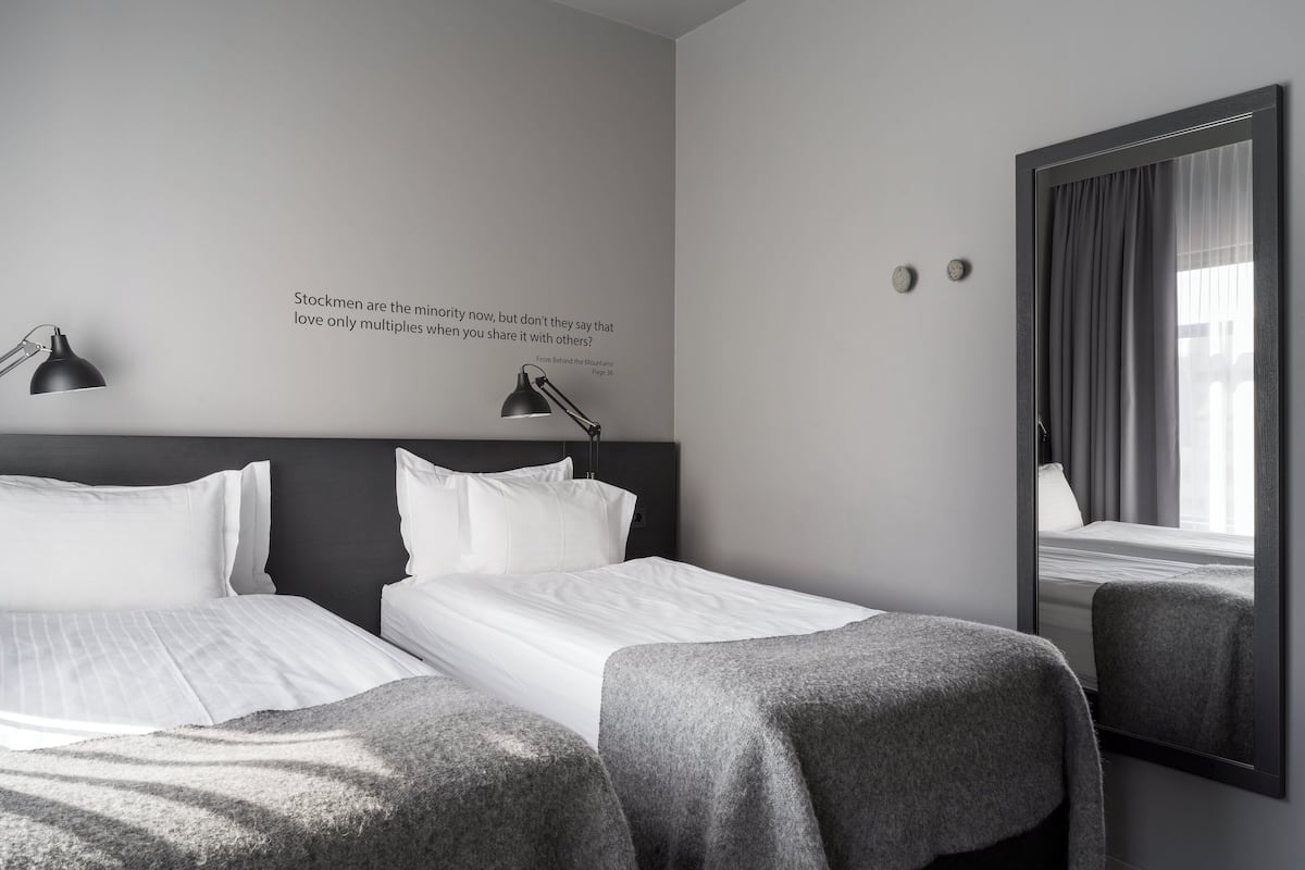Ein Hotelzimmer mit zwei Betten, einem großen Spiegel und einer Wanddekoration.