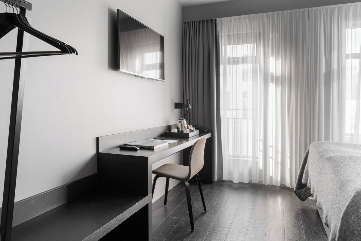 Una camera d'albergo moderna con una scrivania, una sedia e un letto.