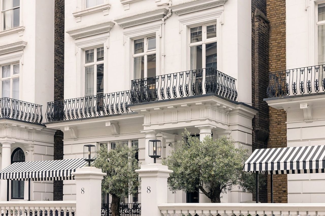 A row of white buildings with black iron balconies and numbered doors.