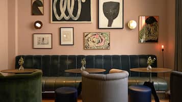 A modern lounge area with a leather sofa, round tables, and various framed artworks on the wall.