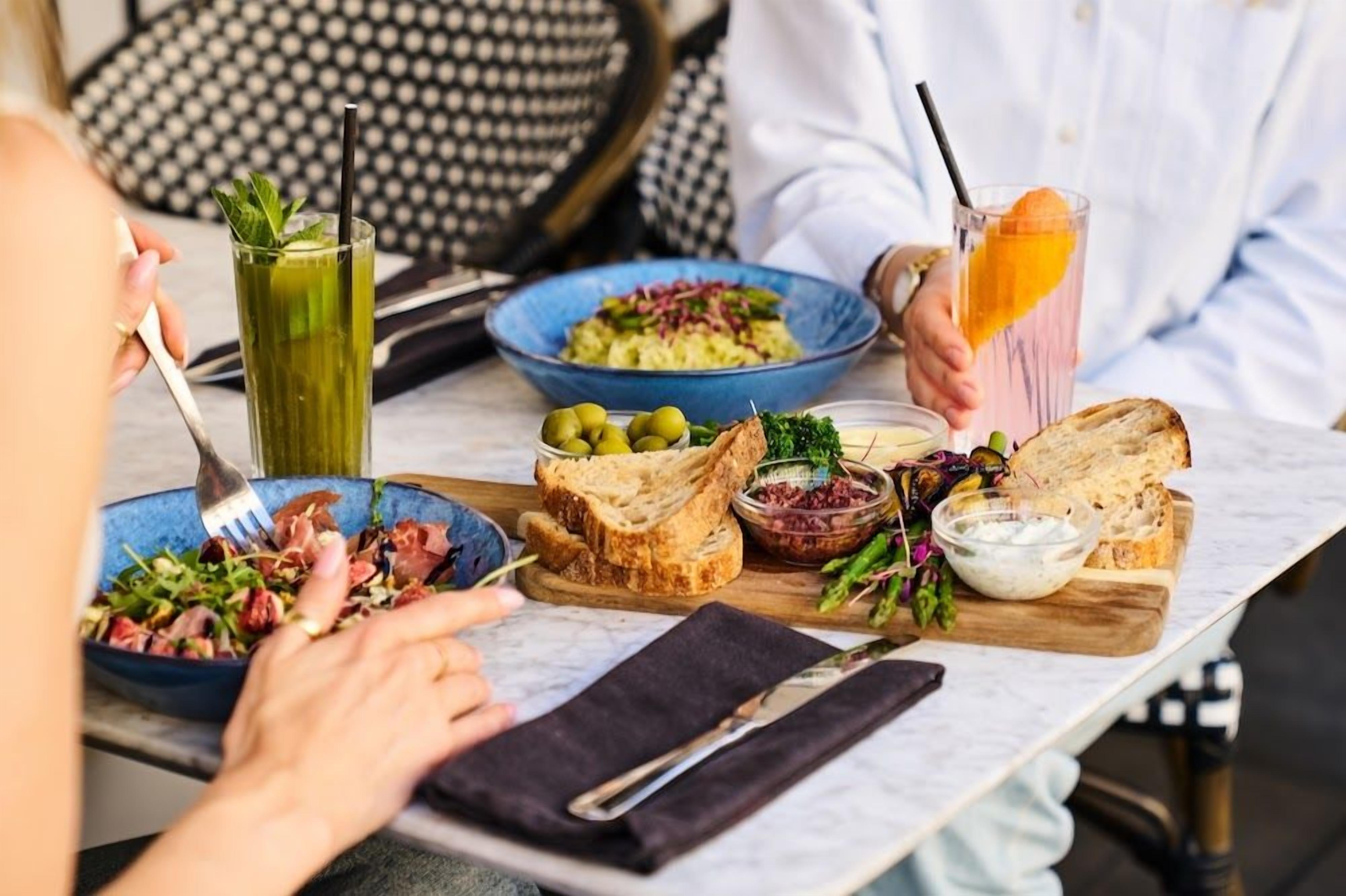A dining table with various dishes, including a salad, bread, and a drink with an orange slice.