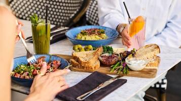 A dining table with various dishes, including a salad, bread, and a drink with an orange slice.