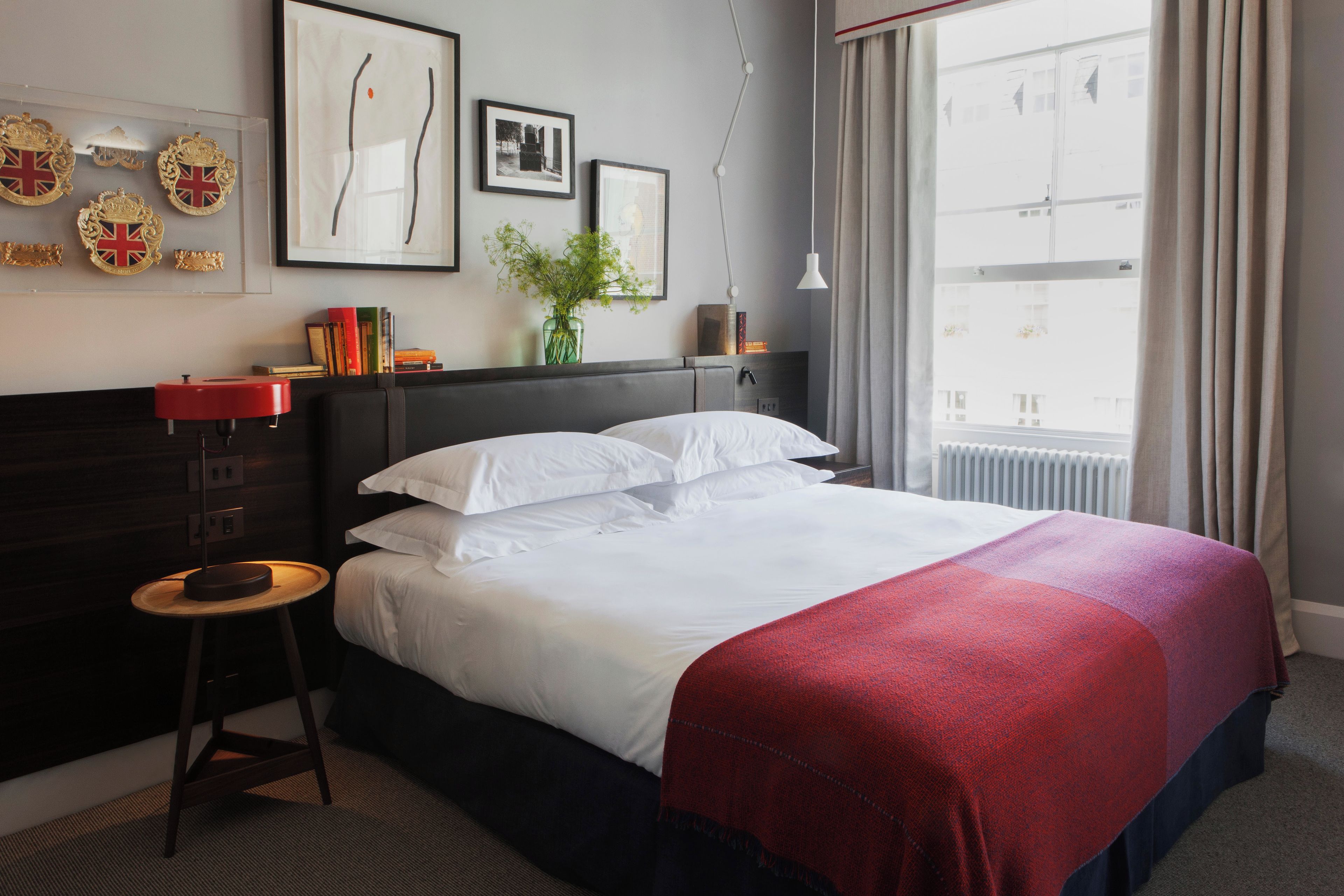 A hotel room with a bed, a nightstand, a dresser, and a window with curtains.