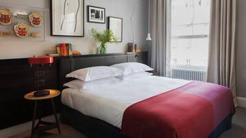 A hotel room with a bed, a nightstand, a dresser, and a window with curtains.