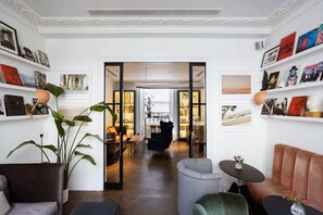 A well-lit interior with a modern living area, a dining space, and a kitchen visible through an open doorway. - The Laslett Hotel (London)