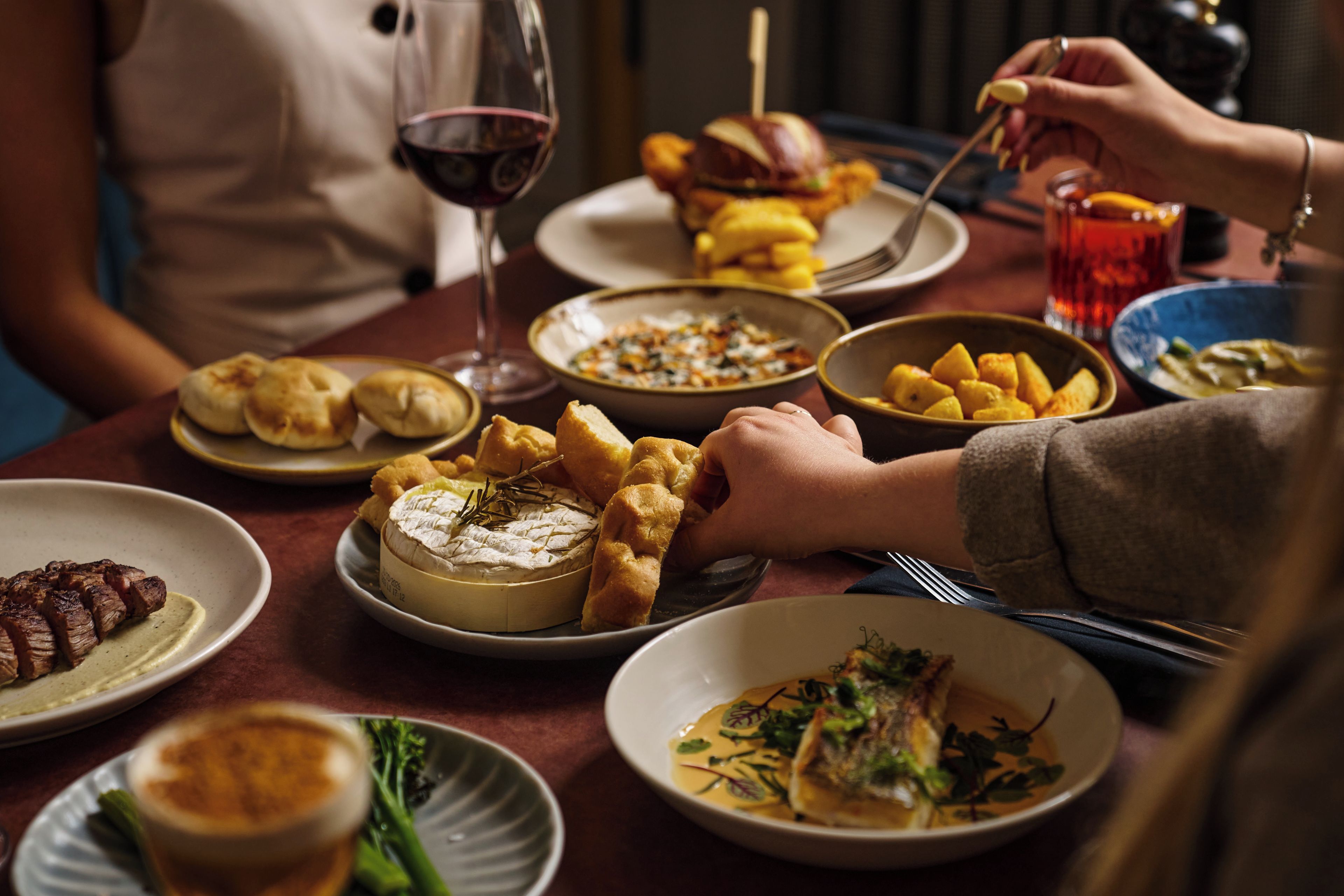 Une table à manger avec différents plats, notamment une assiette de fromage, un bol de soupe et une assiette de viande.