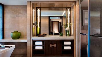 A modern bathroom with a large mirror, a sink, and a vanity with towels.