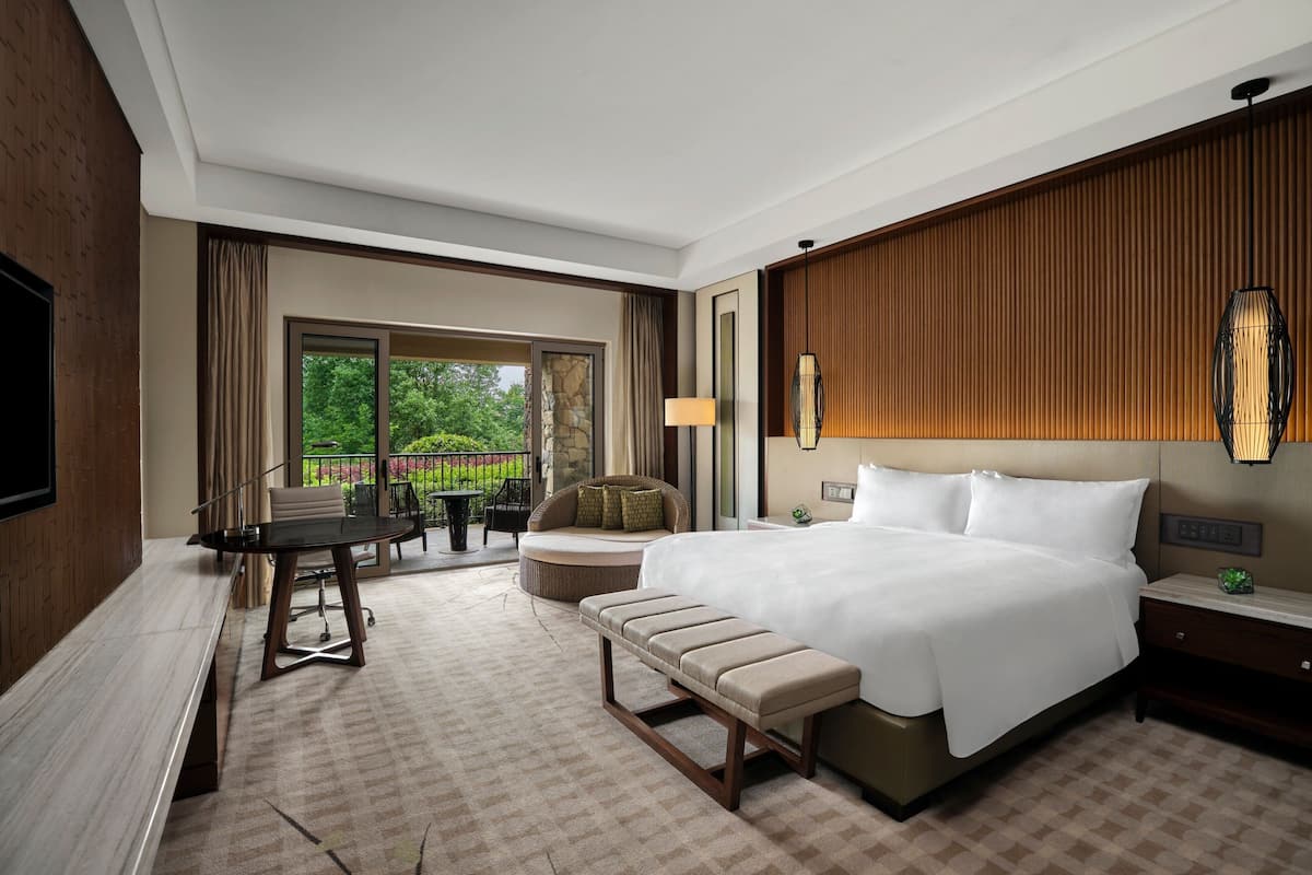 Une chambre d’hôtel avec un grand lit, un bureau, une banquette, un canapé et une vue sur l’extérieur.