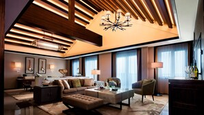 A spacious living room with a high ceiling, modern furniture, and large windows.