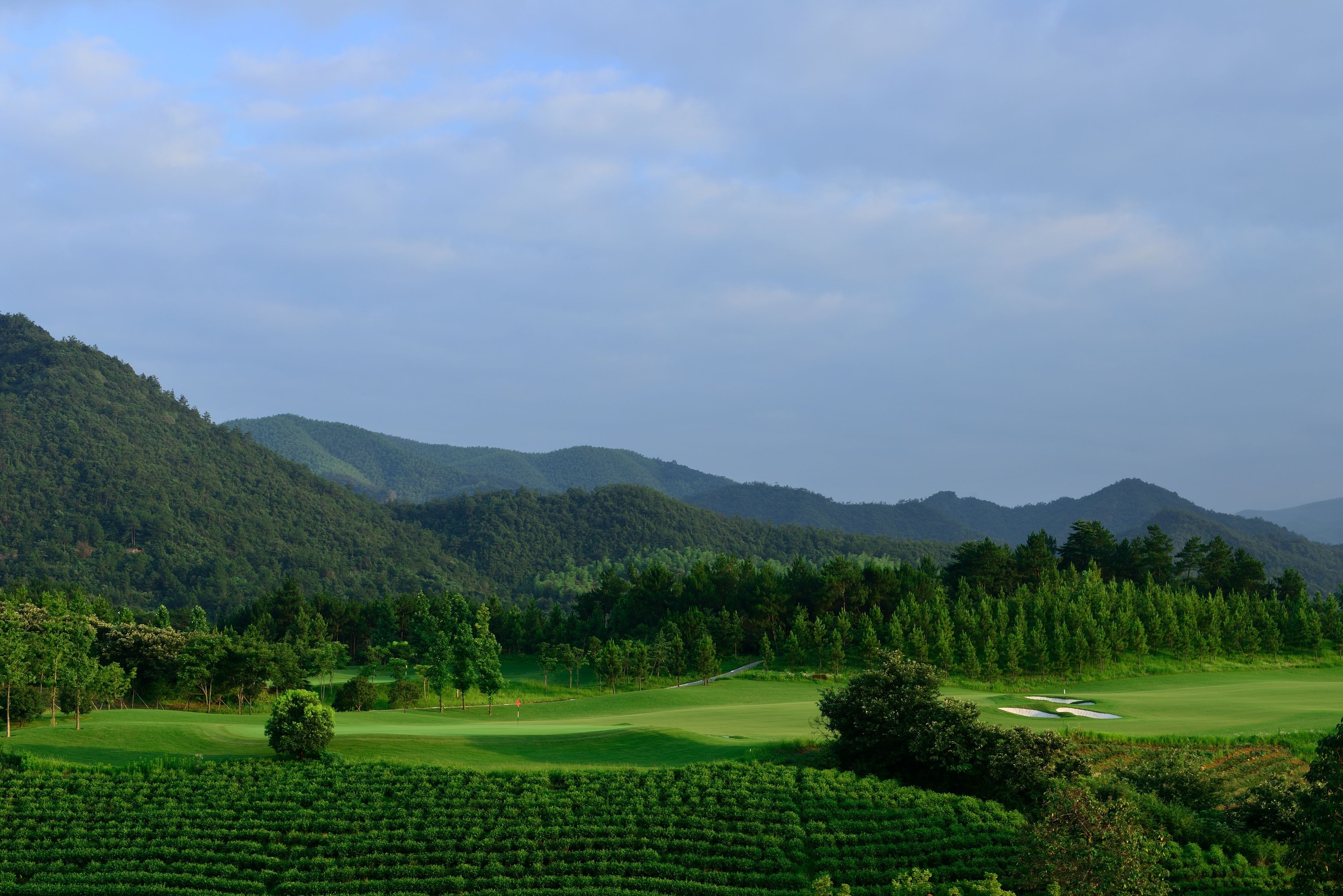 A golf course with lush green hills and a clear sky.
