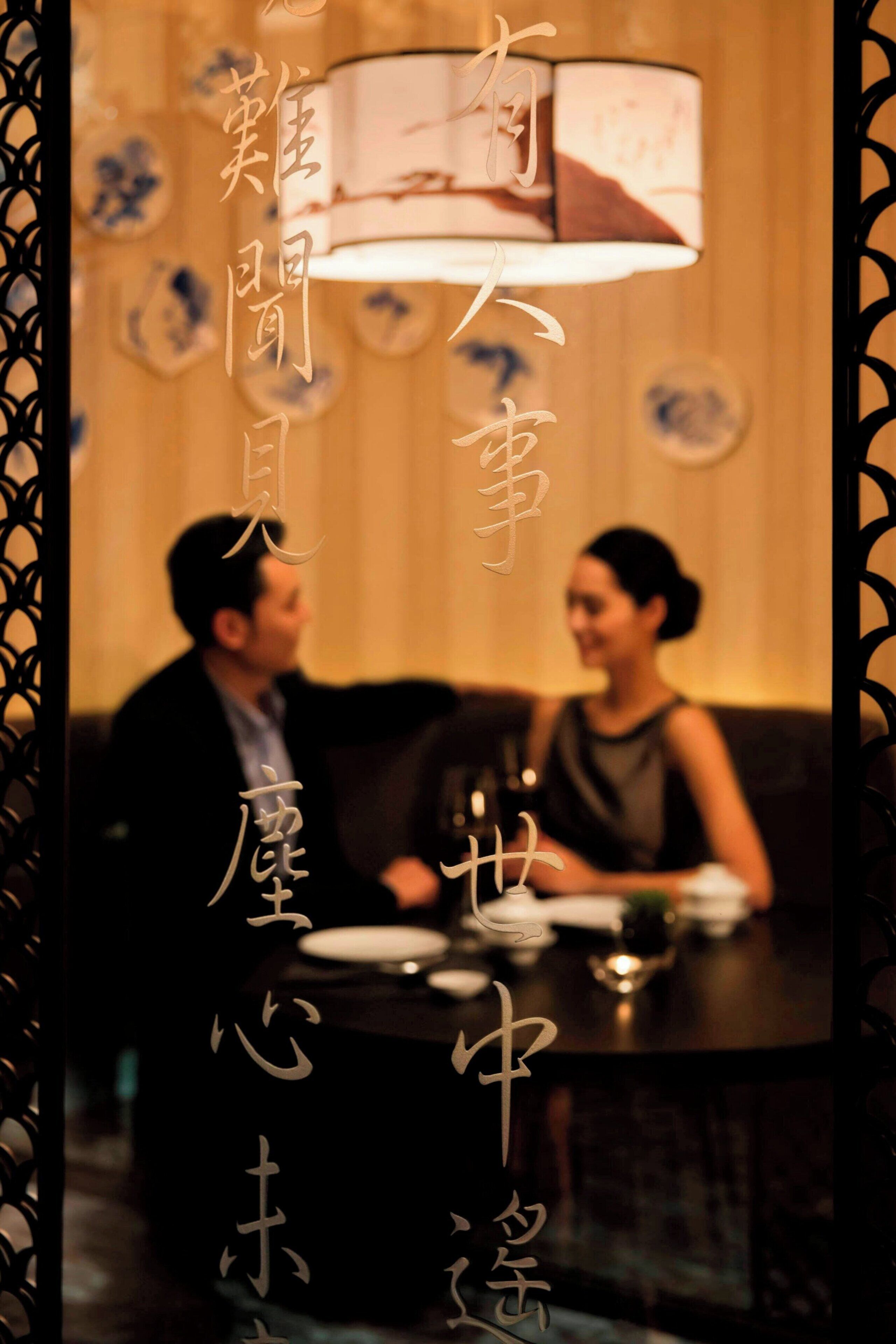 A couple seated at a table in a dimly lit room with traditional decor.