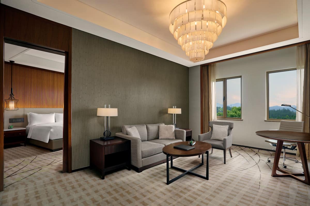 Une chambre d’hôtel comprenant un lit, un canapé, une table basse, un bureau et une vue sur l’extérieur.